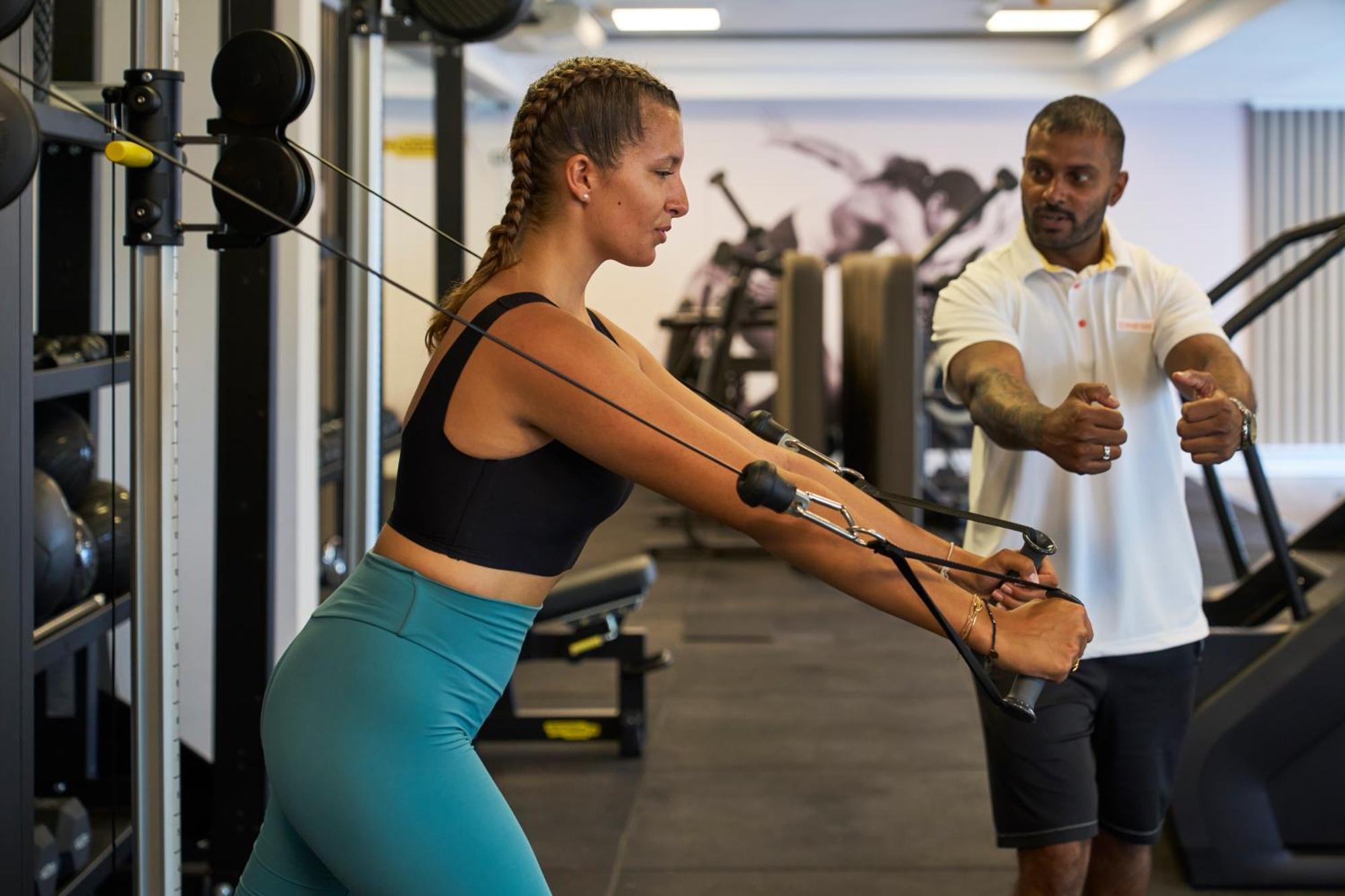 Lux* Belle Mare Resort & Villas Экстерьер фото Personal trainer assisting a woman with a cable row exercise